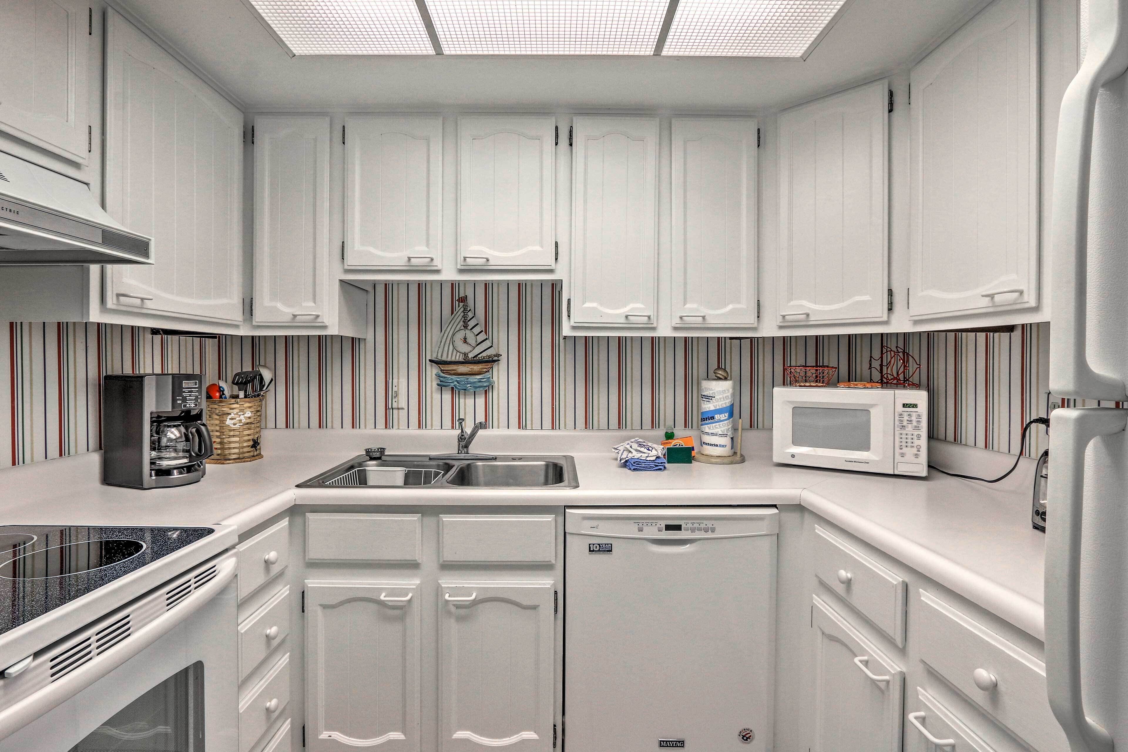 A modern kitchen with white cabinetry, a stainless steel sink, a coffee machine, and a microwave.