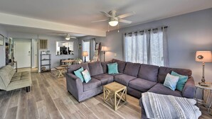 A living room with a sectional sofa, a wooden coffee table, and a ceiling fan.