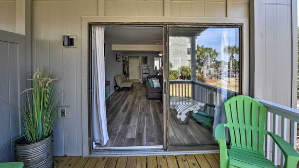 A covered porch with a sliding glass door leading to a living room with a sofa and a dining area.