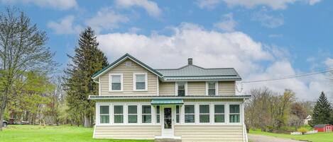 A two-story house with a green roof and a porch.