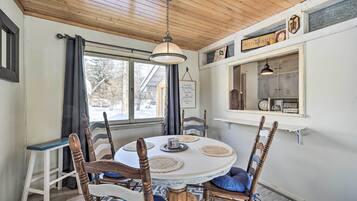 A dining area with a round table, wooden chairs, and a hanging light fixture.