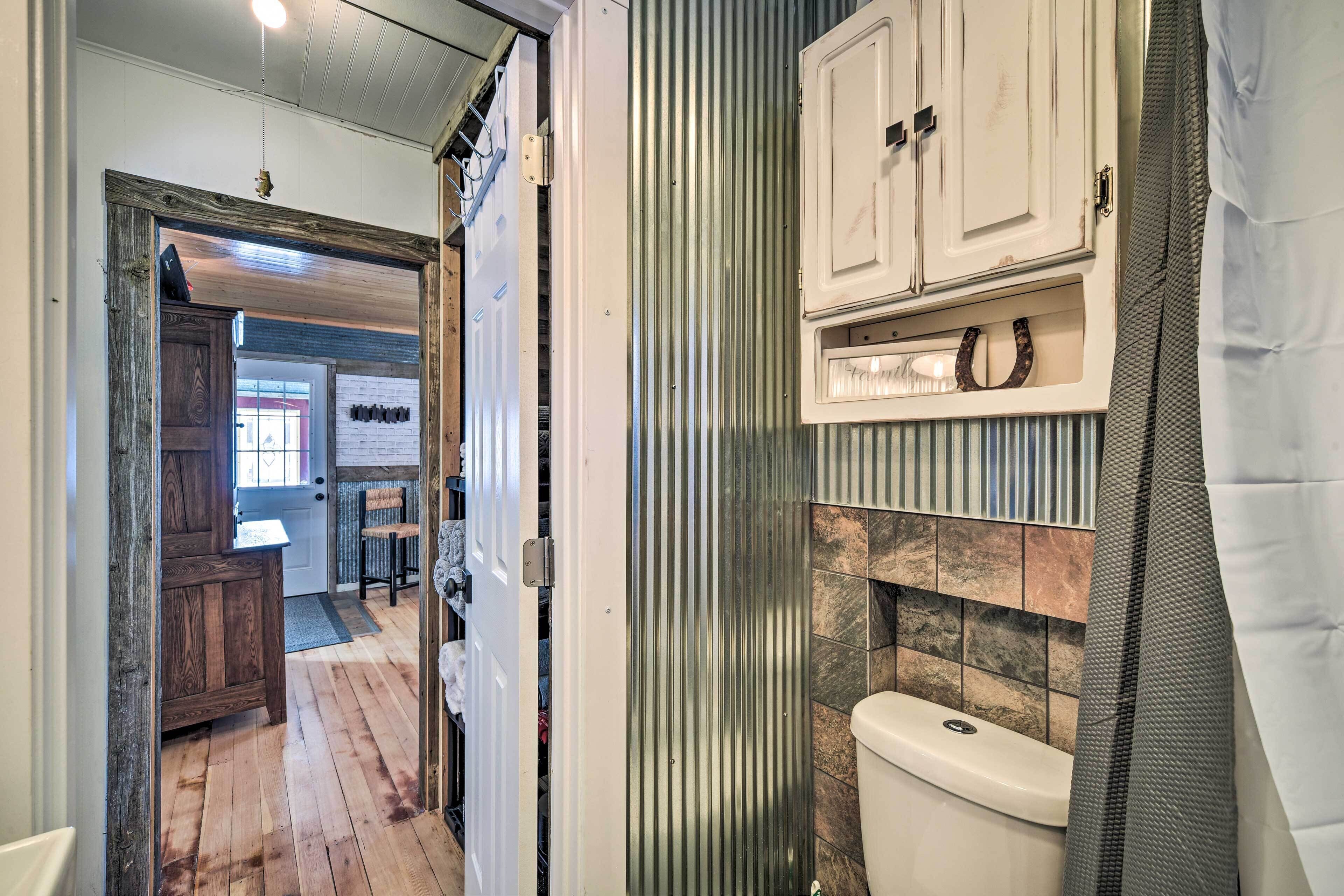 A bathroom with a toilet, a wooden cabinet, and a shower curtain.