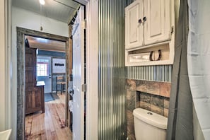 Une salle de bain avec des toilettes, un meuble en bois et un rideau de douche.