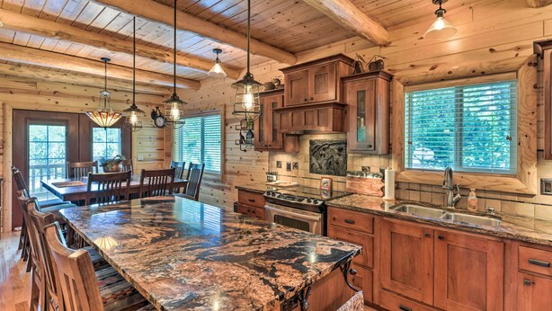 A spacious kitchen with a large island, wooden cabinets, and a stone countertop. - Island Park Cabin w/ Stunning Forest Views! (Island Park)