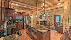 A spacious kitchen with wooden cabinets, a stainless steel refrigerator, and a large island with a granite countertop. - Island Park Cabin w/ Stunning Forest Views! (Island Park)