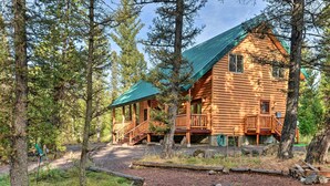 A log cabin with a green roof, surrounded by trees. - Island Park Cabin w/ Stunning Forest Views! (Island Park)