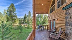 A log cabin with a wooden deck, outdoor seating, and a grill. - Island Park Cabin w/ Stunning Forest Views! (Island Park)