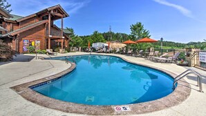 Un espace piscine avec un bâtiment en bois, des chaises longues et un panneau indiquant qu’il est interdit de se baigner.