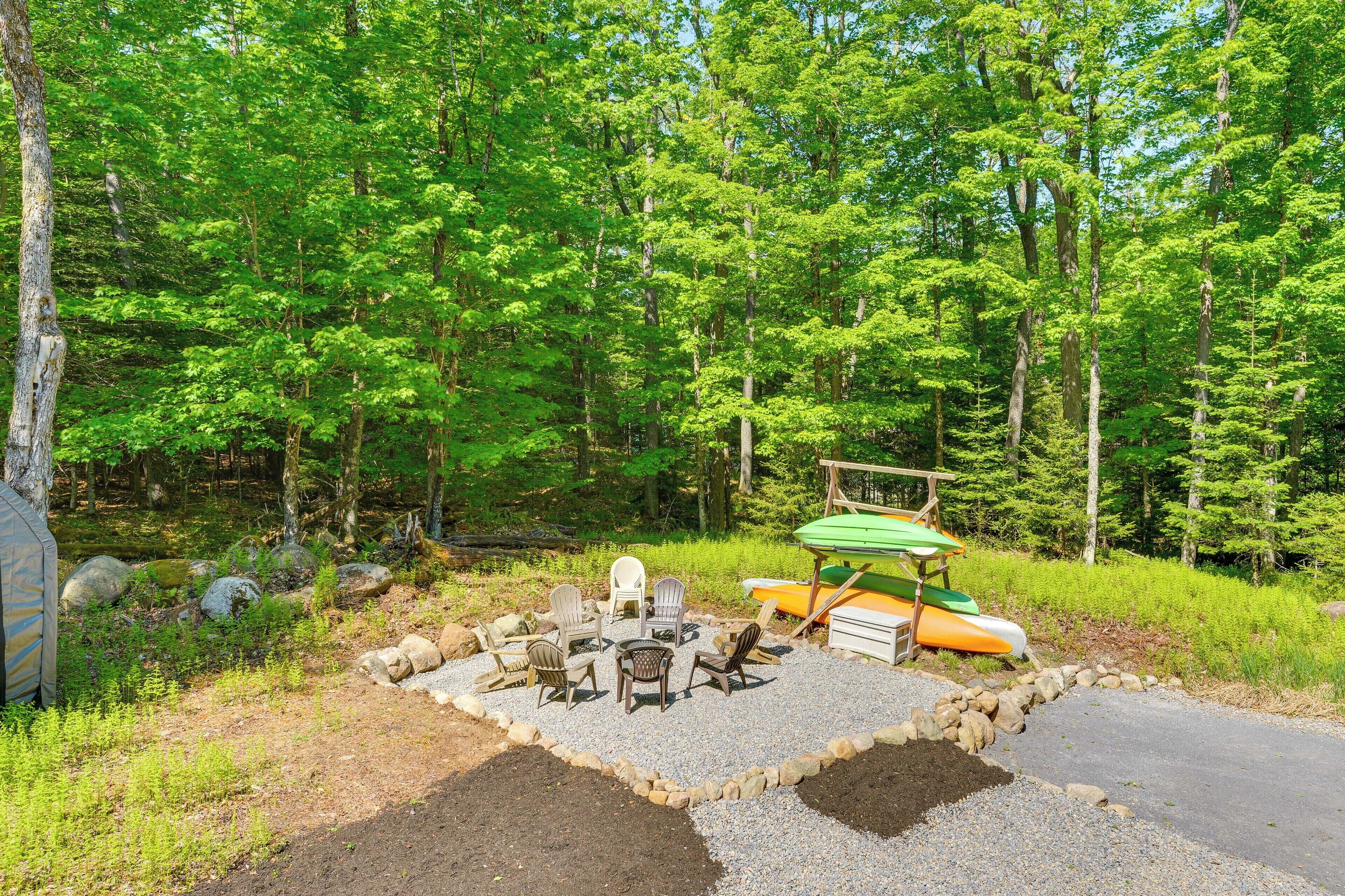 A campsite with a fire pit area, outdoor chairs, and a canoe.
