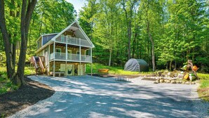 A two-story cabin with a balcony, surrounded by a forest. - Game Room & Hot Tub: Old Forge Home! (Old Forge)