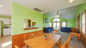 Amplia sala de estar con una mesa de comedor de madera, dos sofás y una cocina al fondo.