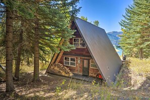 A cabin with a sloped roof, surrounded by trees and a mountainous backdrop. - Irwin A-frame Cabin w/ Deck & Mountain Views! (Irwin)