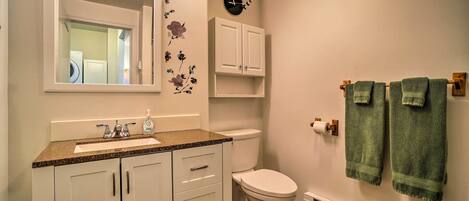 A bathroom with a sink, mirror, toilet, cabinet, and towels.