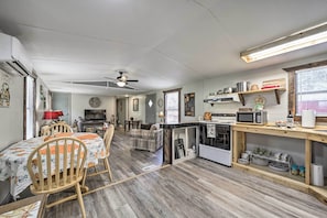 Un espace de vie compact comprenant un coin repas, une cuisine et un petit coin salon.
