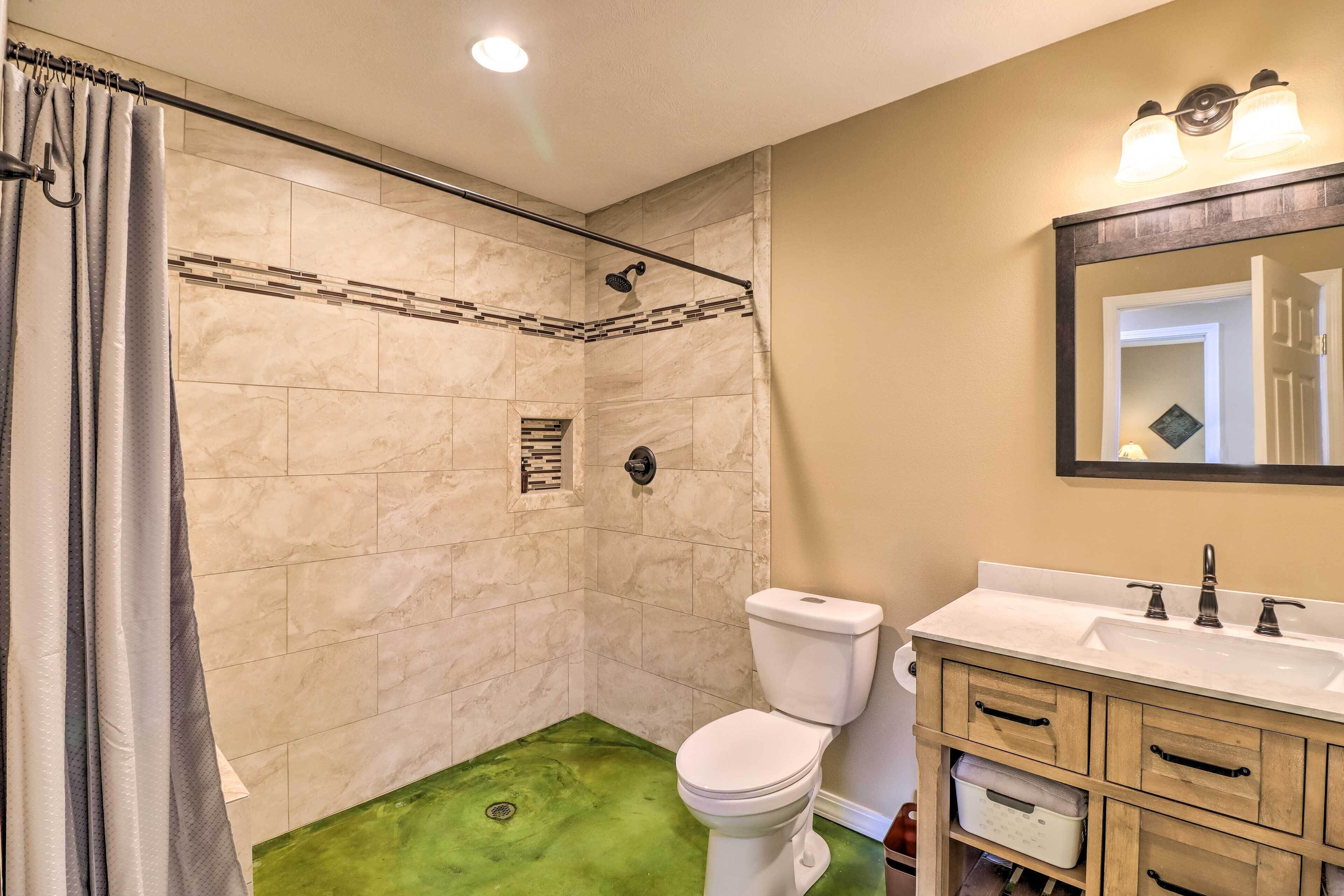 Un baño con ducha, inodoro y tocador con cajones.