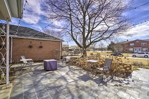 Une terrasse avec un sol en pierre, des sièges d’extérieur et des guirlandes lumineuses.