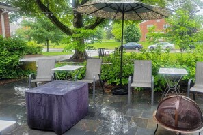 Eine Terrassensitzgruppe im Freien mit Steinböden, überdachten Sitzplätzen und einem großen Sonnenschirm.