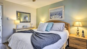 Een netjes ingerichte slaapkamer met een bed, nachtkastjes, een spiegel en een schilderij aan de muur.