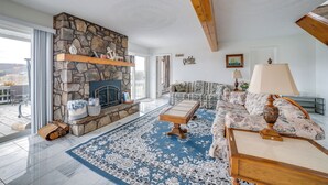 A living room with a stone fireplace, a sofa, a coffee table, and a large window. - Alpine Lake Resort Home: Stunning Lake Views! (Terra Alta)