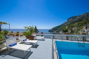 A rooftop pool with lounge chairs and potted plants, overlooking a coastal view. - Villa Arte- Luxurious Villa in Ravello (Minori)