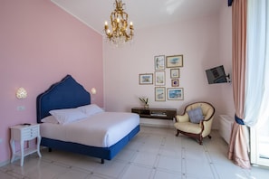 A bedroom with a bed, bedside table, chair, wall art, and a chandelier. - Villa Arte- Luxurious Villa in Ravello (Minori)