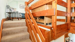 Una escalera de madera con peldaños alfombrados que conduce a una zona con cama tipo entrepiso.