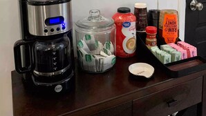 Una encimera de cocina con una cafetera, un escurreplatos para tazas y diferentes alimentos.
