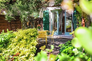 Relax in a serene garden setting with a patio area, complete with a table and chairs for dining or unwinding.