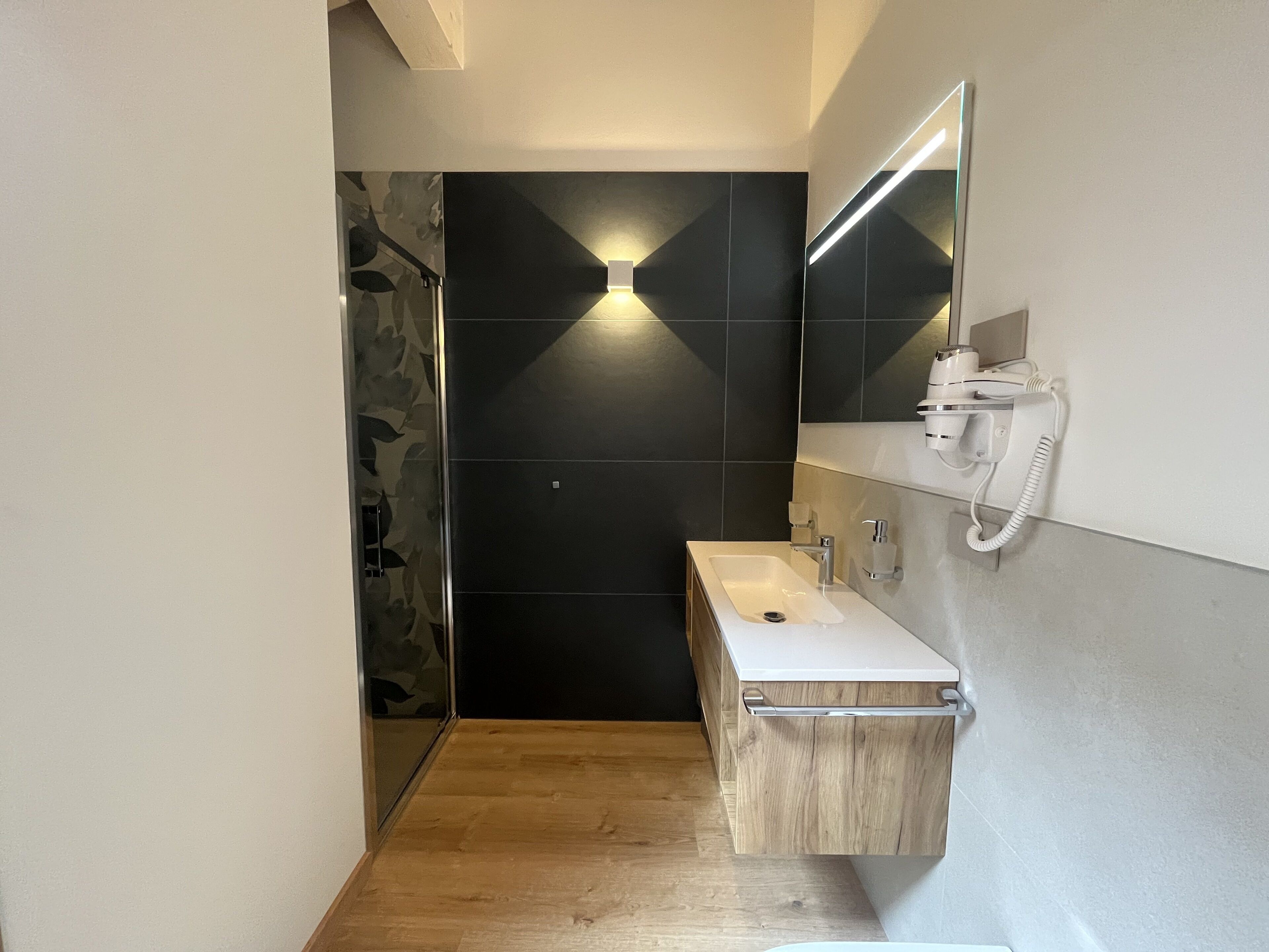 Ein modernes Badezimmer mit einem Holzausziehtisch, einem weißen Waschbecken und einem Spiegel.