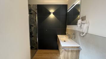 Ein modernes Badezimmer mit einem Holzausziehtisch, einem weißen Waschbecken und einem Spiegel.