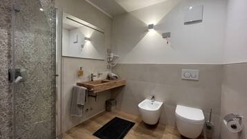 Un bagno moderno con cabina doccia in vetro, mobile lavabo in legno, un bidet e un water.