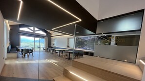A modern office space with a large desk area, a seating area with a sofa, and a staircase with integrated lighting. - Le Rocce Val di Non - Quality Room & Breakfast  (Ville d'Anaunia)