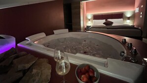 A spa room with a large bathtub, a bowl of strawberries, and a glass of water. - Le Rocce Val di Non - Quality Room & Breakfast  (Ville d'Anaunia)