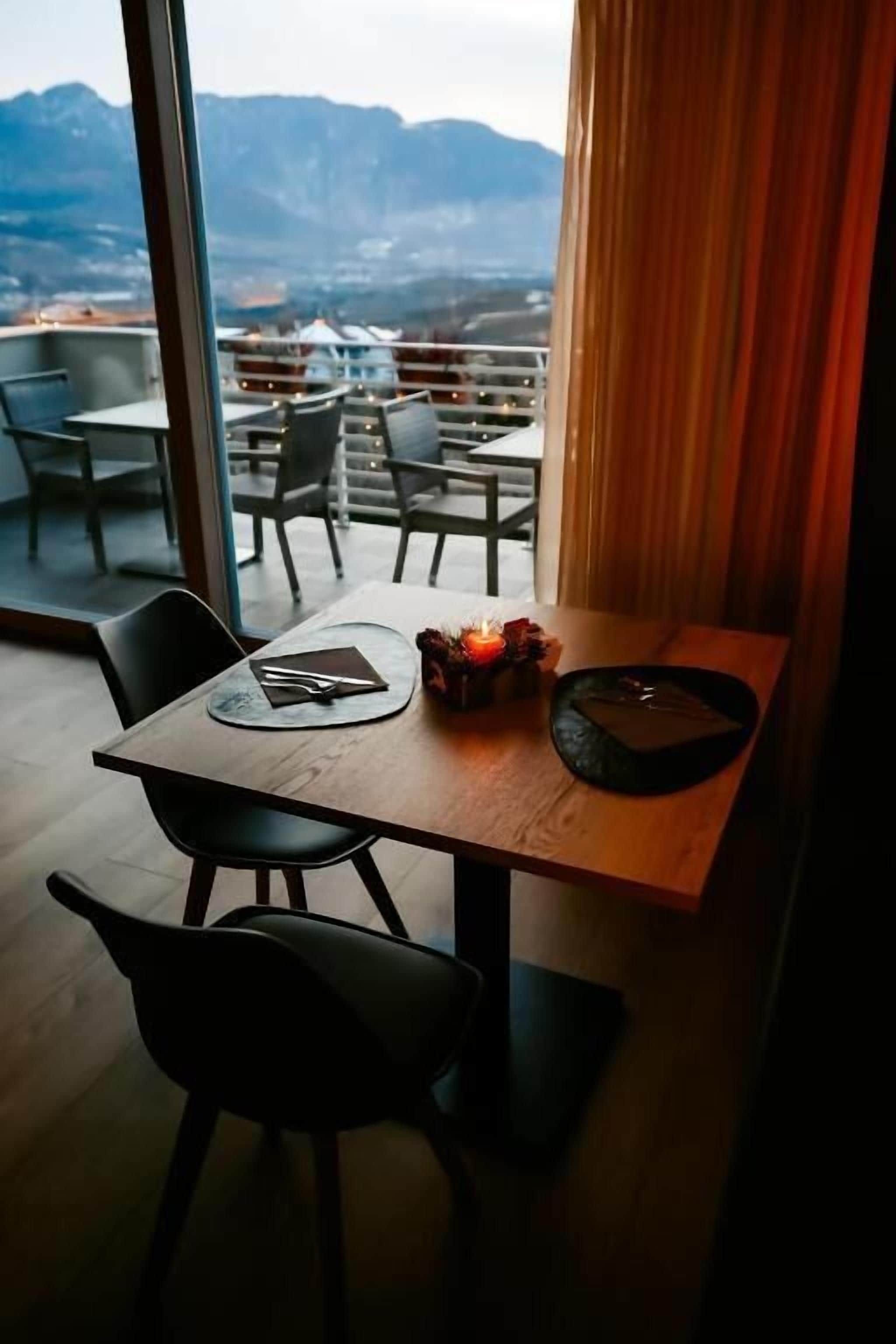 A dining area with a table set for two, a candle, and a view of mountains.