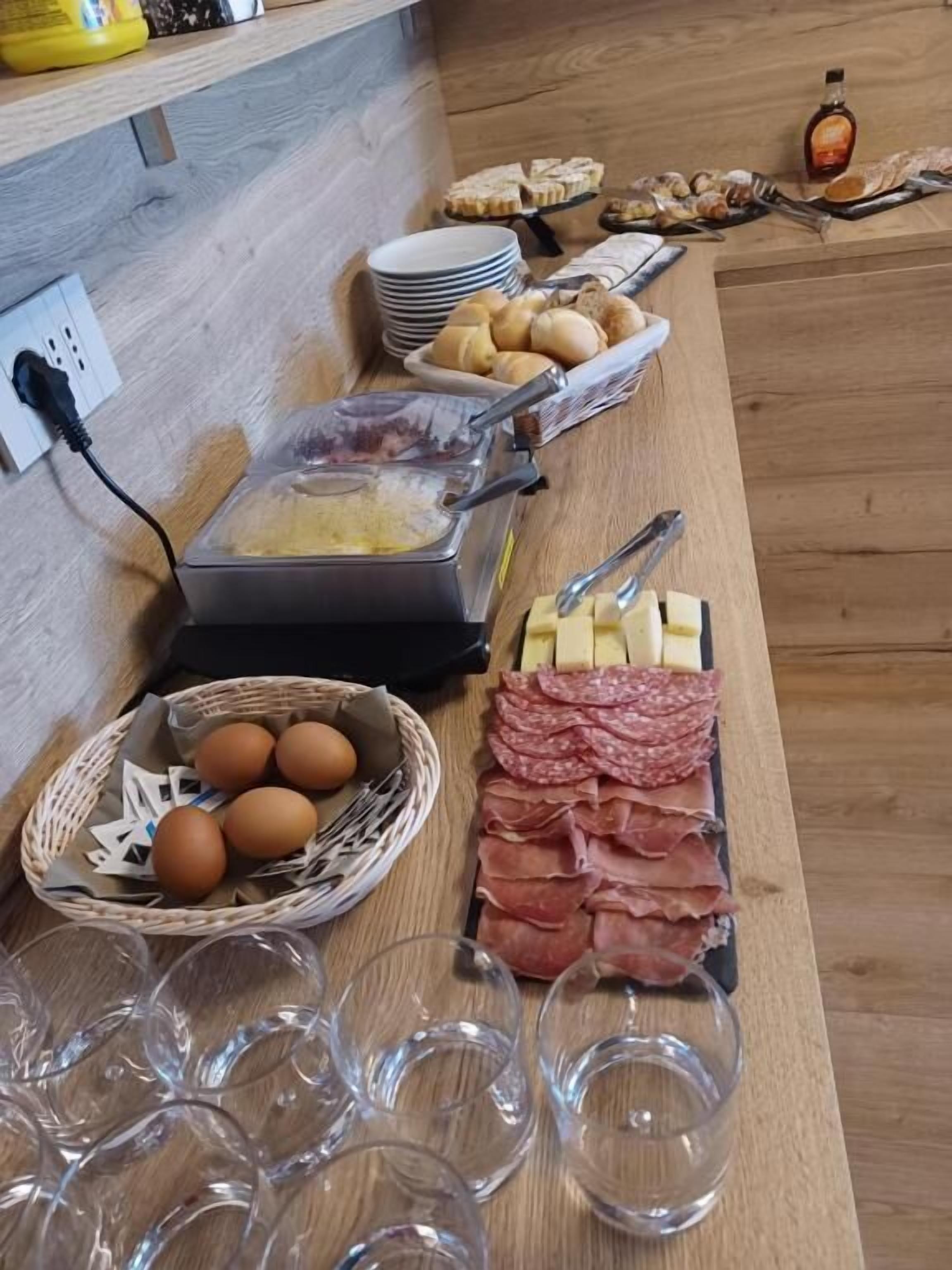 A buffet table with various food items including eggs, cheese, and meats, along with plates and glasses.