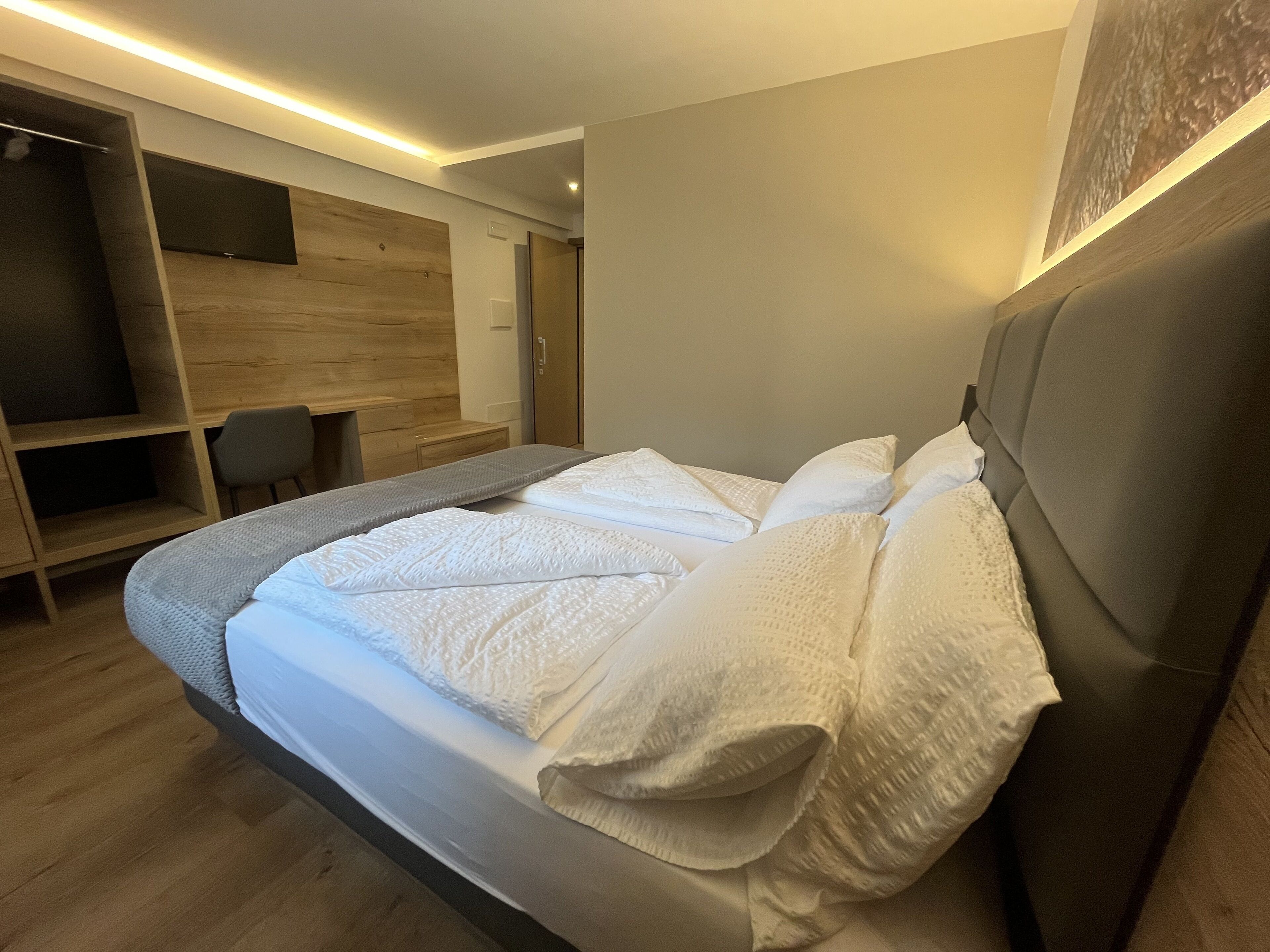 Ein modernes Schlafzimmer mit einem großen Bett, einem Holzschrank und einem Schreibtisch.