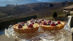 A glass dessert stand with tarts on a balcony overlooking a mountainous landscape. - Le Rocce Val di Non - Quality Room & Breakfast  (Ville d'Anaunia)
