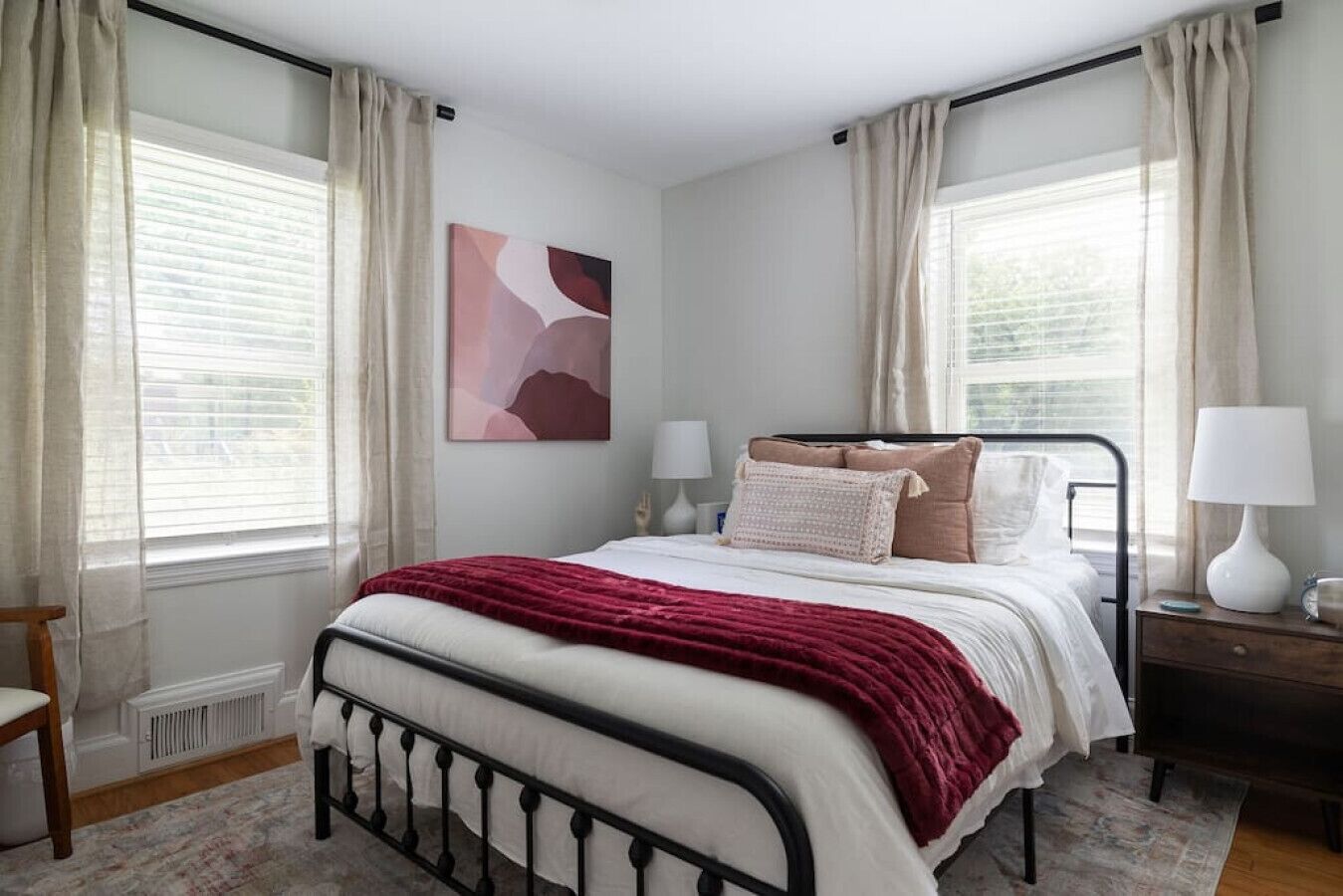 Un dormitorio con cama, dos mesitas de noche, un radiador y una ventana con cortinas.