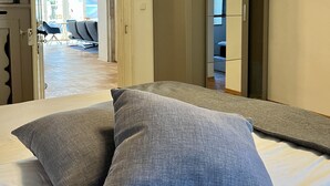 A bedroom with a bed, two pillows, a wooden ceiling, and an open door leading to a hallway. - Fewo Rosenstraße (Tegernsee)