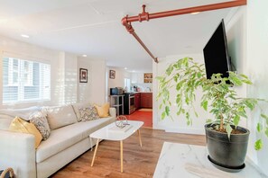 A living room with a sofa, coffee table, and a potted plant.