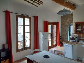 Una cocina con mesa, refrigerador, microondas y pared de piedra.