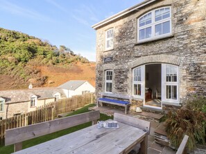 A stone building with a wooden deck and a bench. - Cliffside (Tintagel)