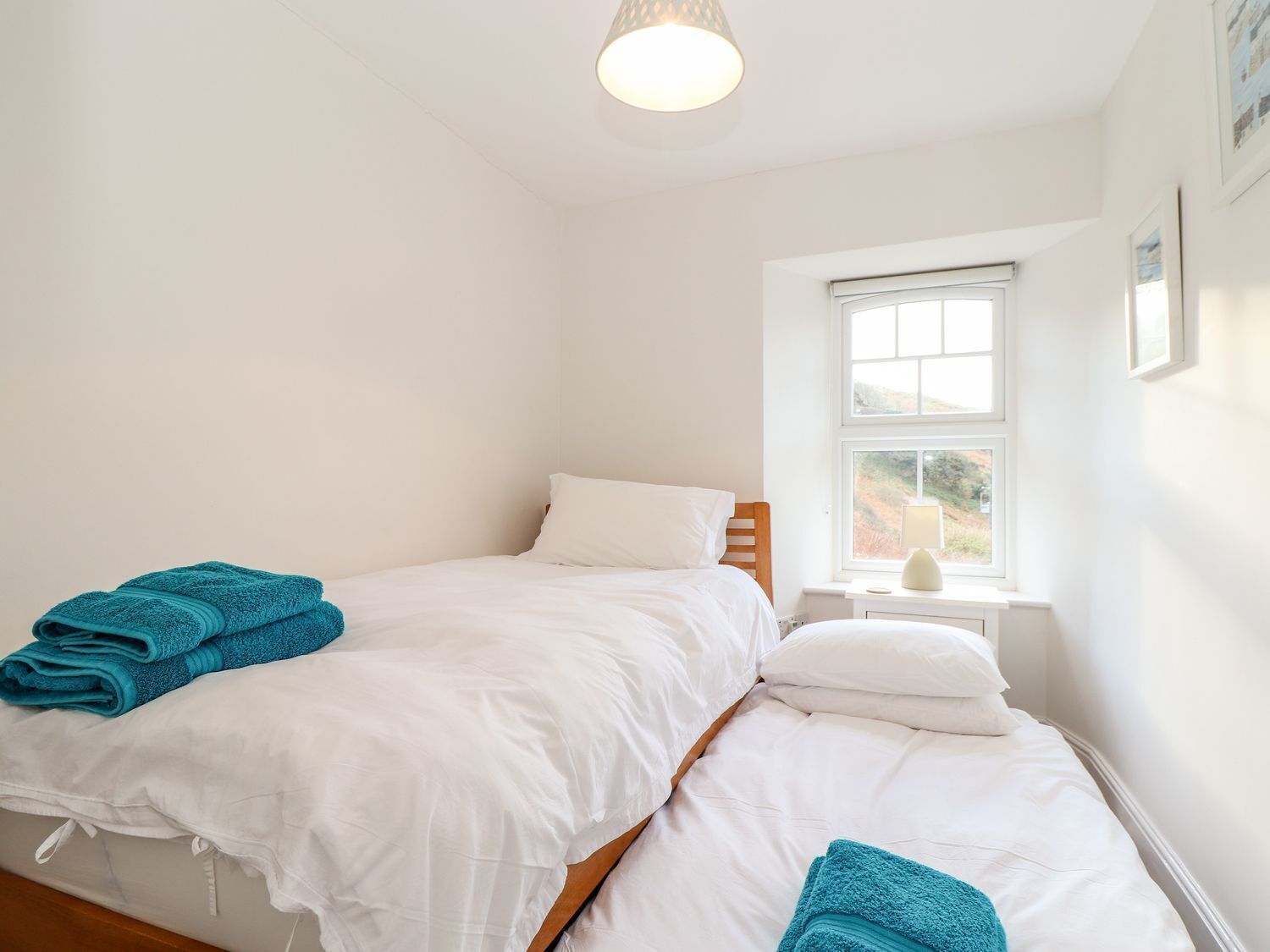 A bedroom with two beds, white bedding, and teal towels.