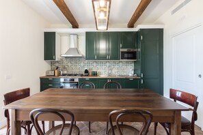 Una cocina con armarios verdes, una mesa de comedor de madera y sillas.