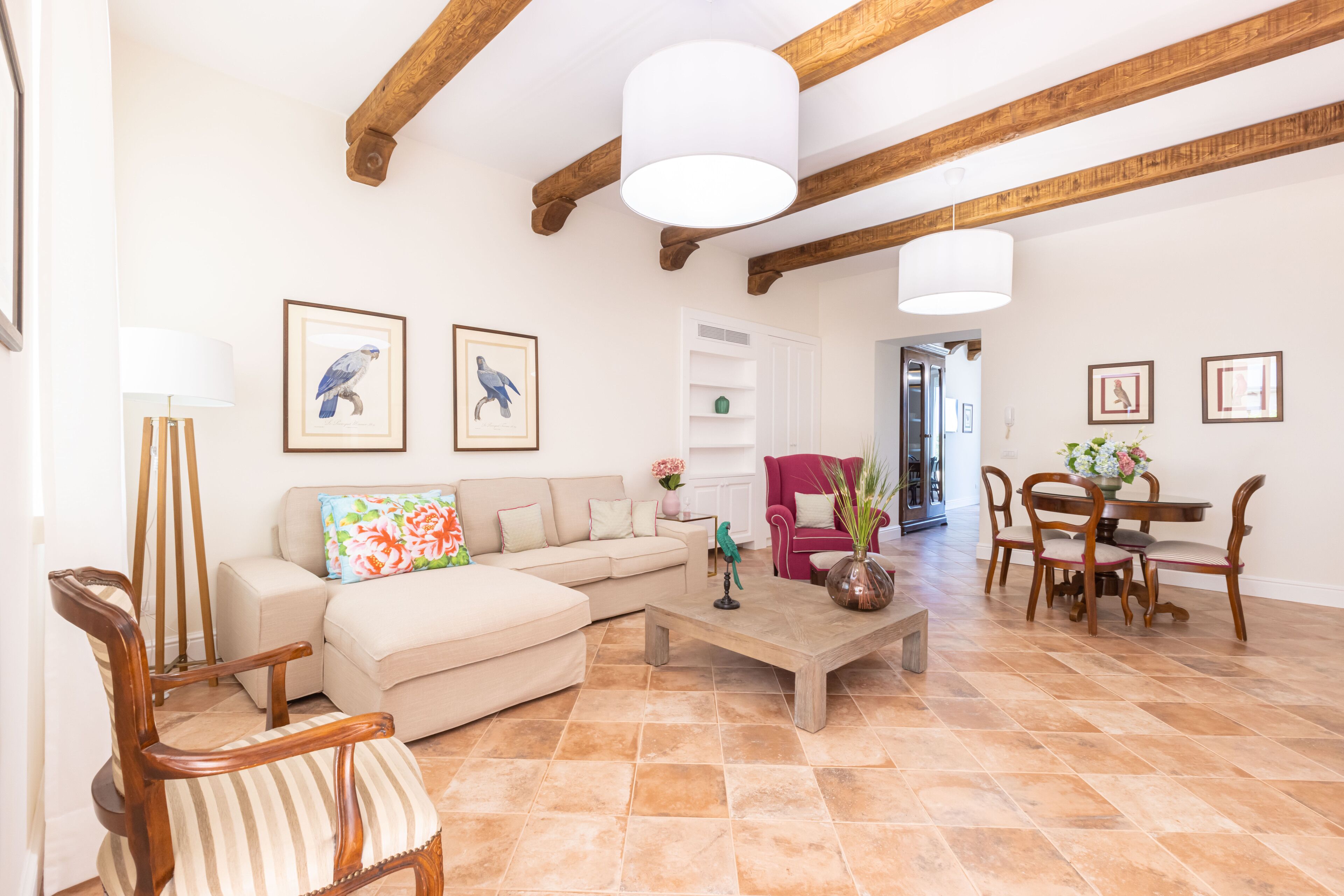 A spacious living room with a sofa, chairs, a coffee table, and a dining area with a table and chairs.