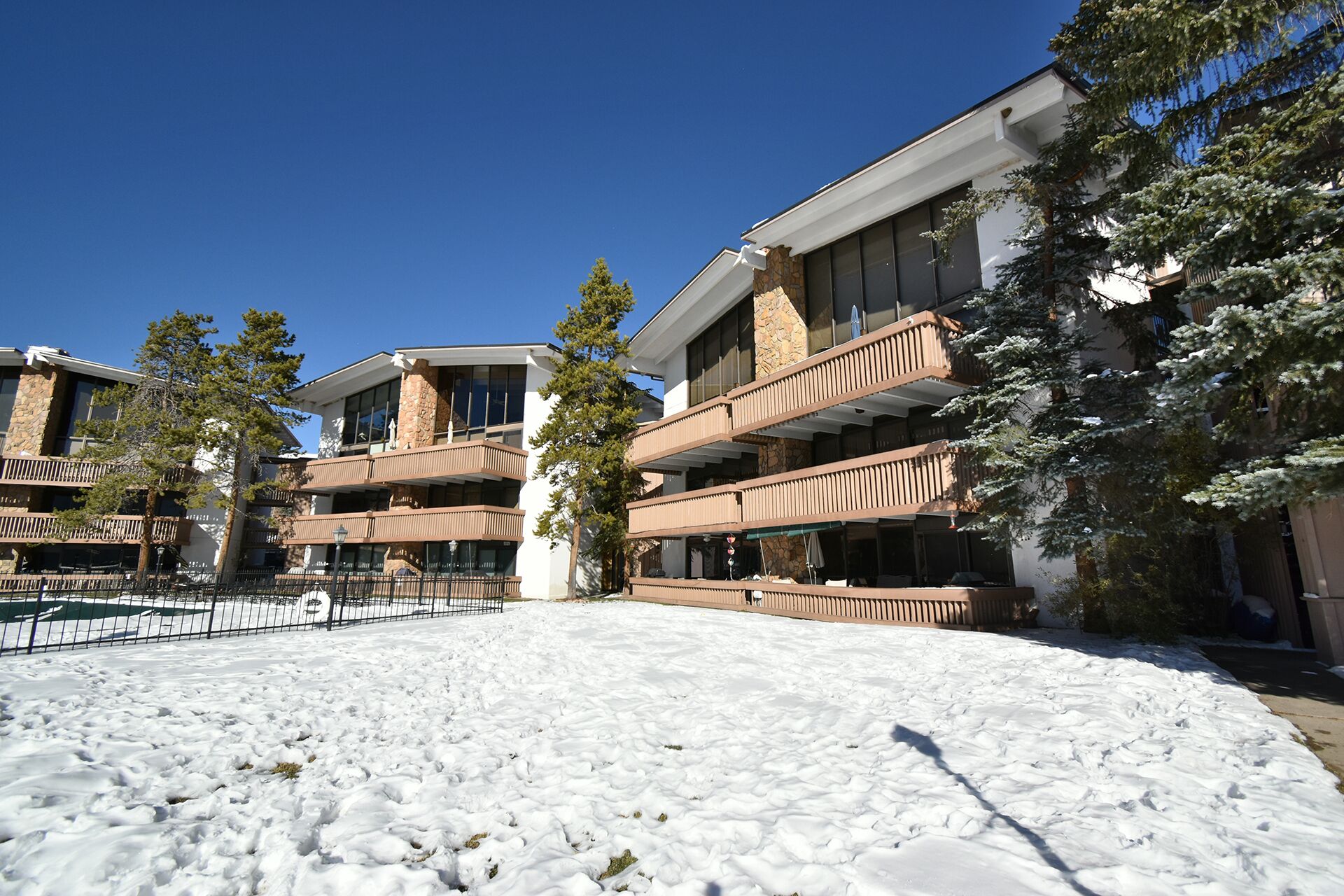 Un hôtel à plusieurs étages, doté de balcons, d’une façade en pierre et d’un parterre enneigé.