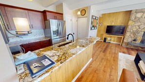 Una cocina moderna con encimeras de granito, electrodomésticos de acero inoxidable y armarios de madera.