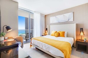 A modern hotel room with a large bed, a desk, and a view of the cityscape. - Oceanfront Oasis: Luxury, Sunrise Views, Resort (Hollywood)