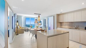 Une cuisine moderne dotée d’un îlot central, d’un coin repas offrant une vue agréable et d’une grande fenêtre donnant sur la mer.