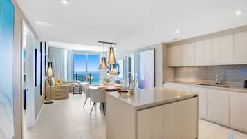 A modern kitchen with a central island, a dining area with a view, and a large window overlooking the sea.